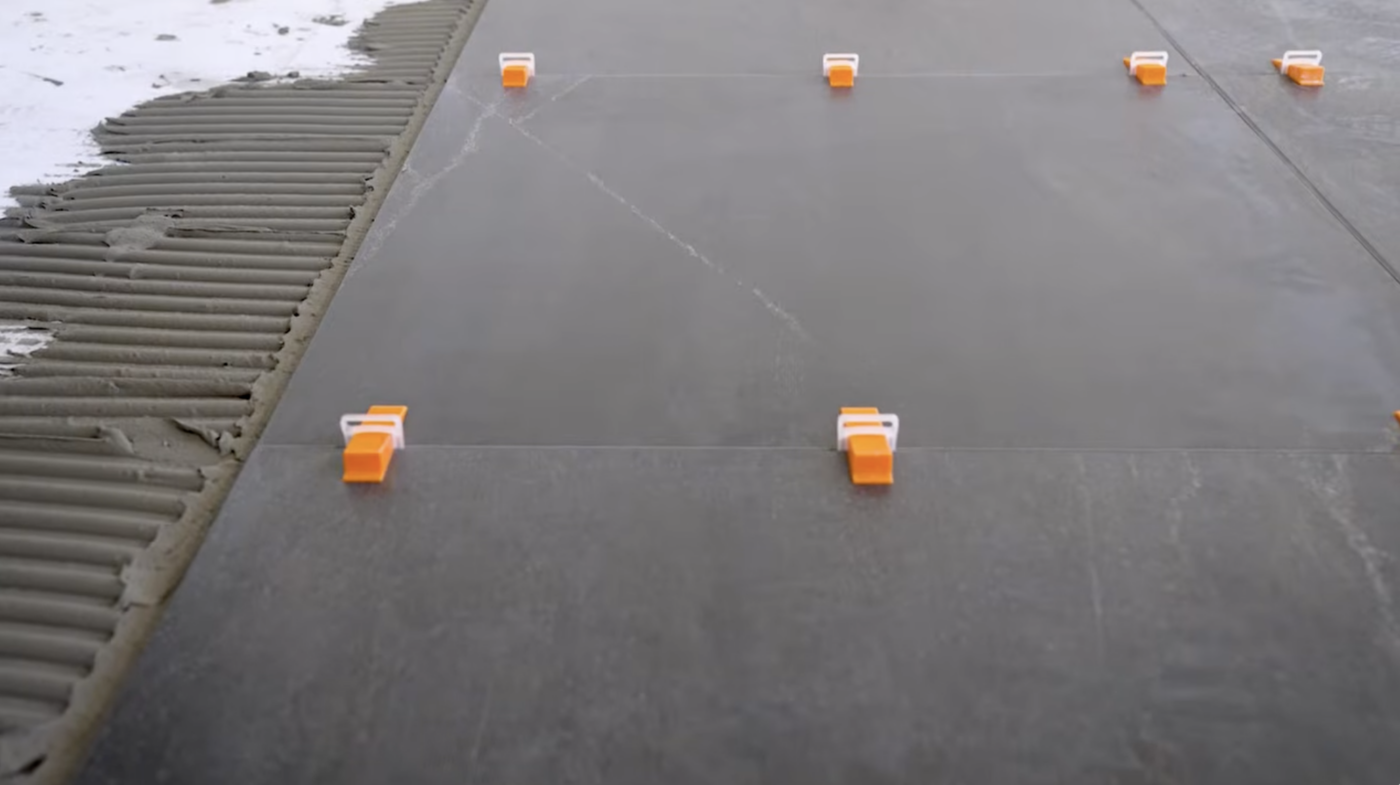 Geplaatste tegels met Levelit nivelleerclips en spieën tijdens het uitharden van de tegellijm.